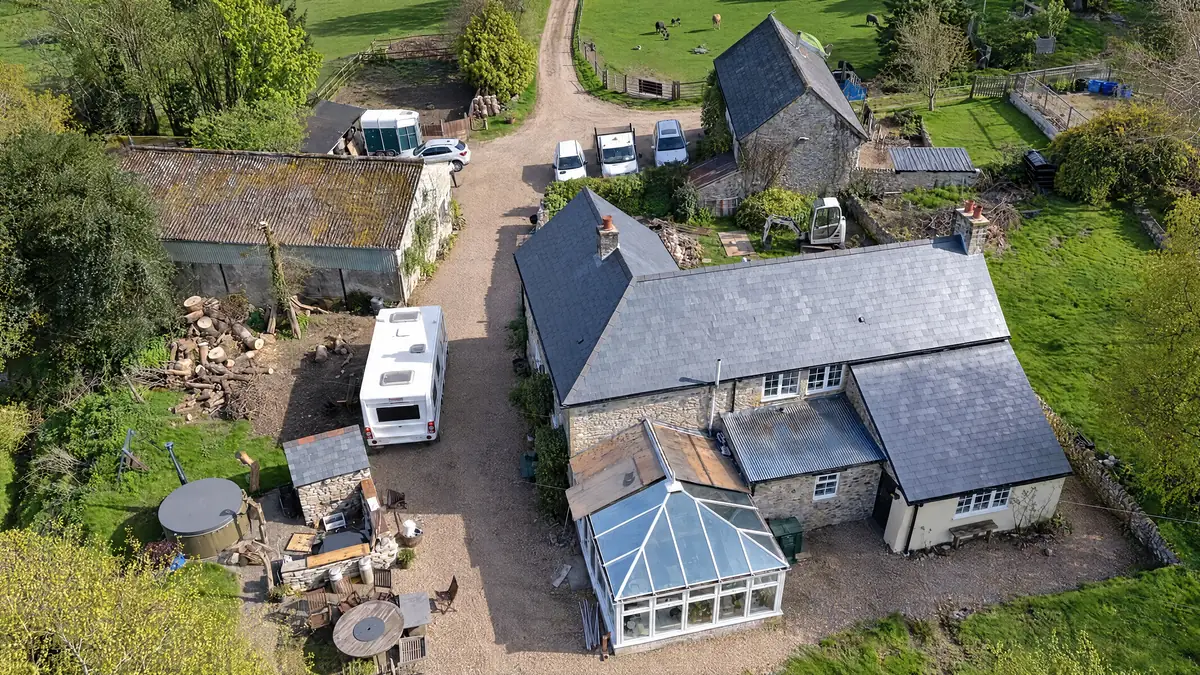Drone view of a stone farmhouse with a slate roof and conservatory