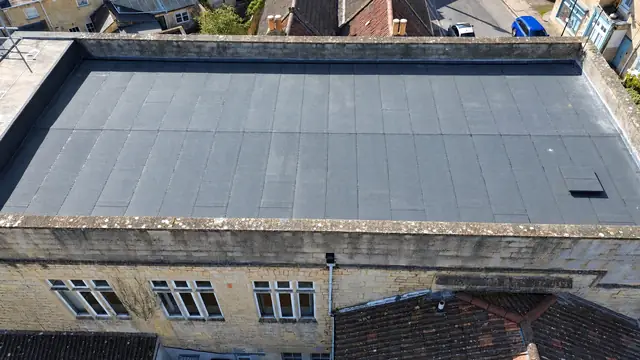 Side-on drone view of a new felt flat roof and stone parapet