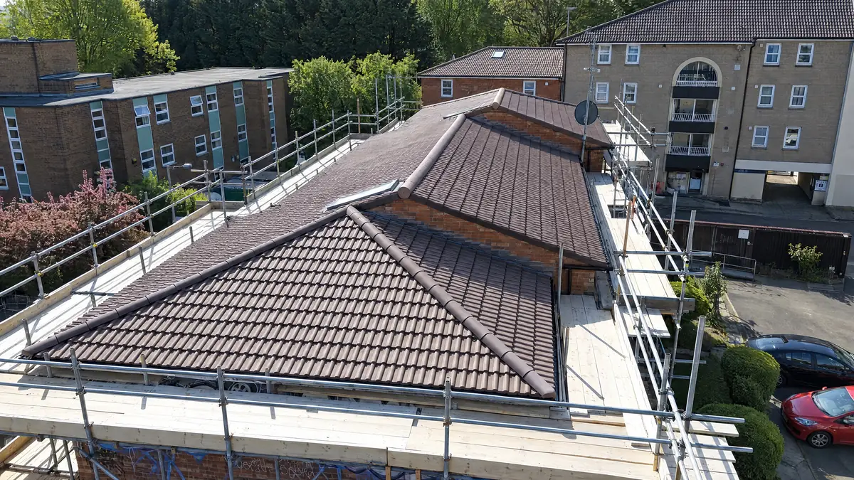 Close aerial view of a newly tiled hip roof with scaffold in place