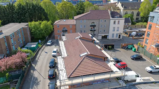 Aerial view of a commercial building with a new tiled hip roof and full scaffold