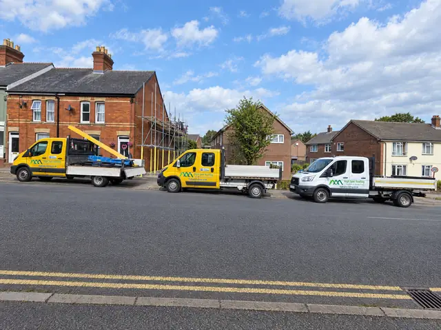 High Spec Roofing's fleet of trucks parked outside a re-roofing job