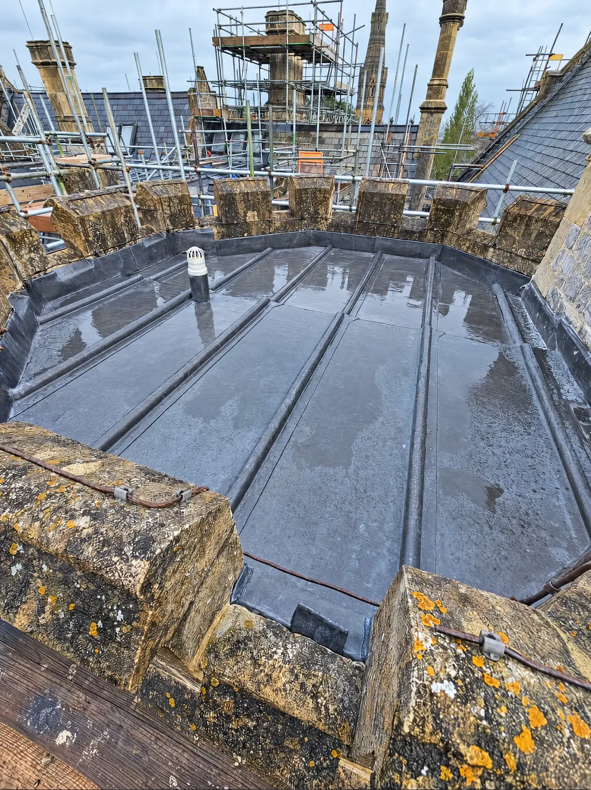New lead roll flat roof behind the stone battlements of a church tower