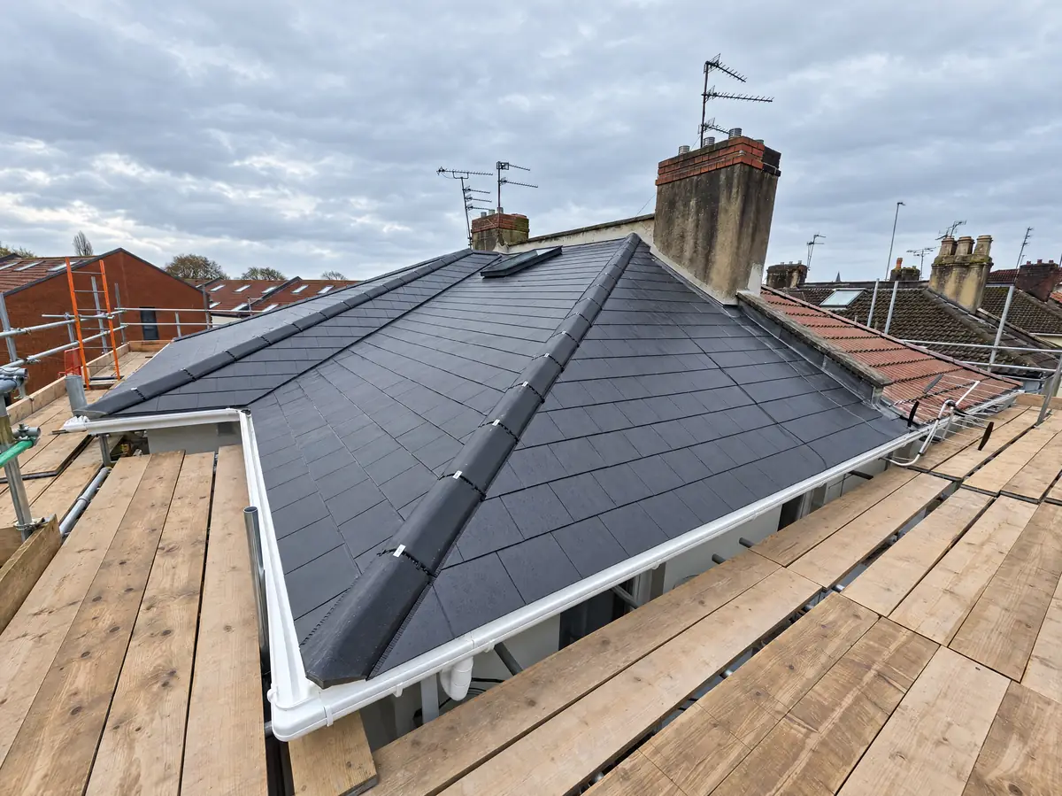 Newly installed slate-effect tiled hip roof on a terraced house, seen from the scaffold